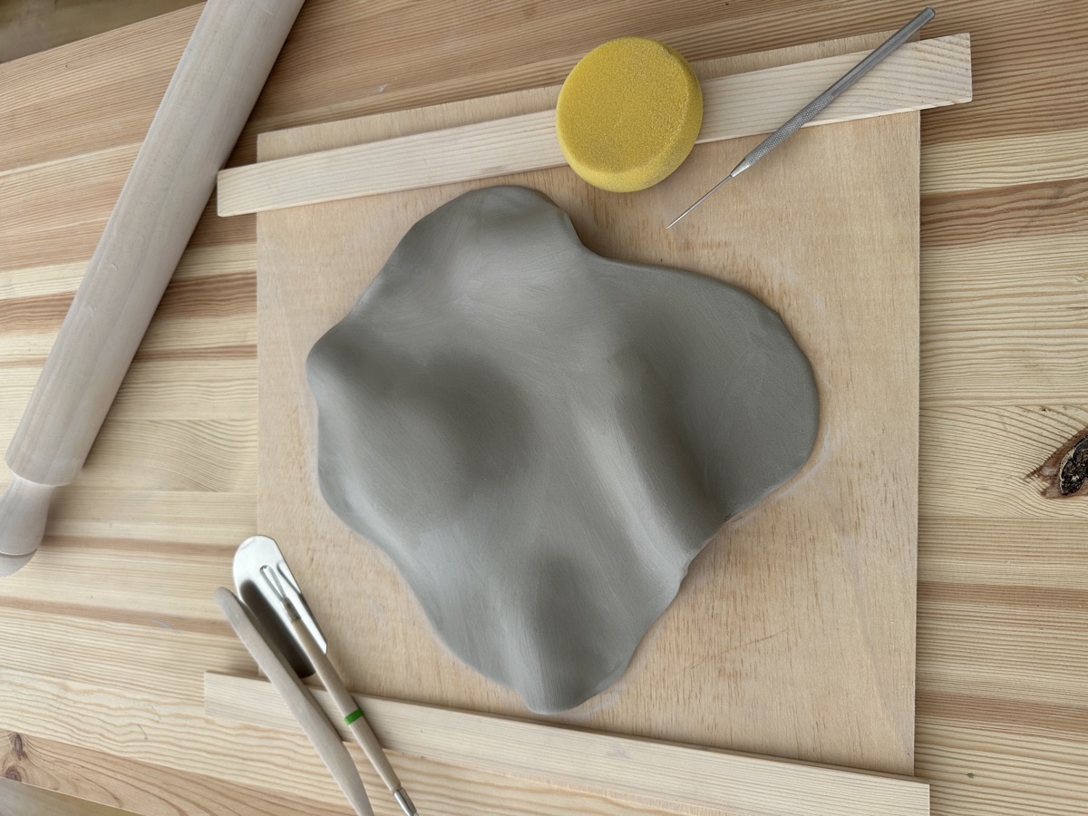 Handbuilt clay form and pottery tools on a work table