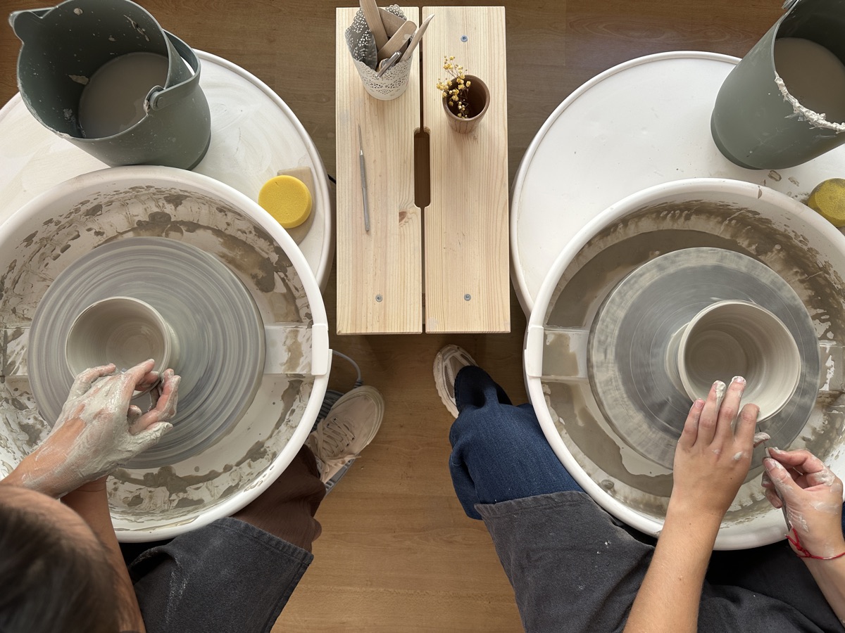 Two people working side by side at pottery wheels at PURACERÂMICA in Lisbon