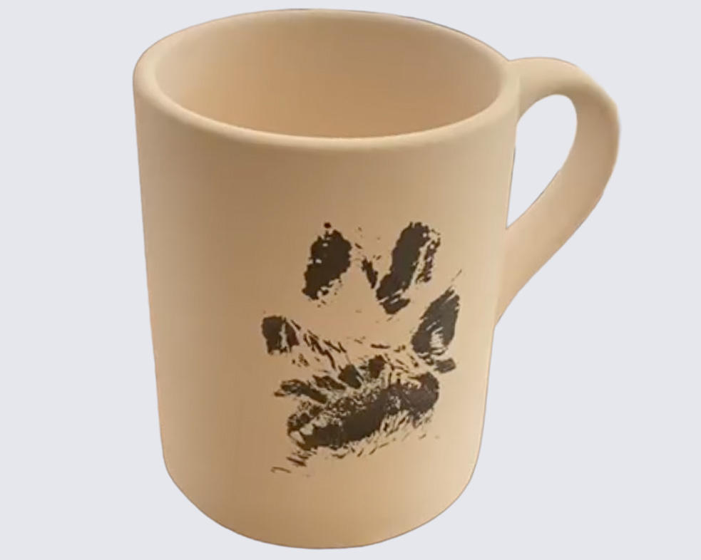 Dog making paw print on ceramic mug